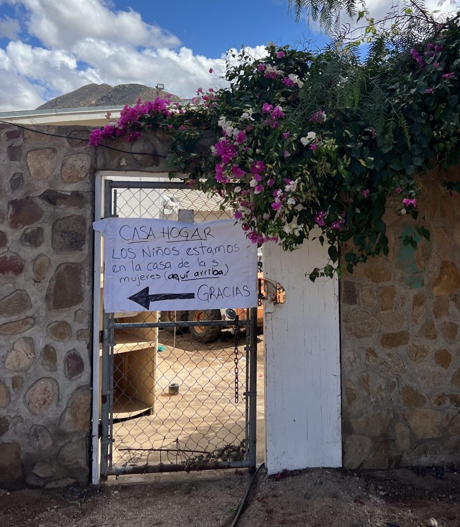 After the Storm in Maneadero The sign on the gate is handwritten: "Casa Hogar. Los niños estamos en la casa de las mujeres (aquí arriba). Gracias." The children are at the women's house, just up here. Thank you.